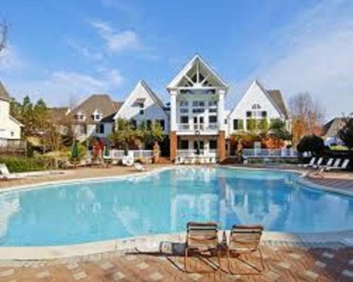 a large swimming pool with two chairs in front of a house at King's Creek Resort by Endless Resorts in Williamsburg