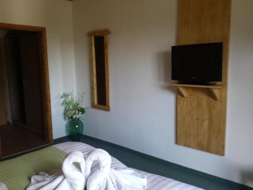 a room with a bed with a television and towels at Pension Alpenrose in Sankt Sigmund im Sellrain