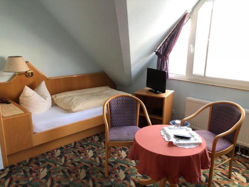 a small room with a bed and two chairs and a table at Pension Preussenstraße Leipzig in Leipzig