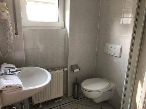 ein Bad mit einem Waschbecken, einem WC und einem Fenster in der Unterkunft Pension Preussenstraße Leipzig in Leipzig