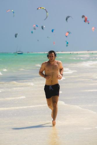 a man is walking on the beach at The Zubeida Boutique Resort in Diani Beach