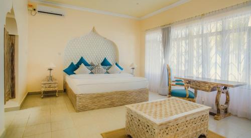 1 dormitorio con cama extragrande y mesa en The Zubeida Boutique Resort, en Diani Beach