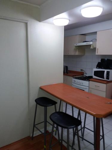 a kitchen with a wooden table and two stools at Depto a pasos de Metro Irarrazaval in Santiago
