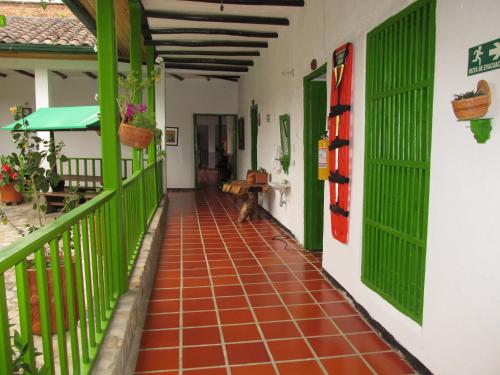 a hallway with green doors and a cat sitting on the floor at Spa Posada 4 Esquinas in La Uvita