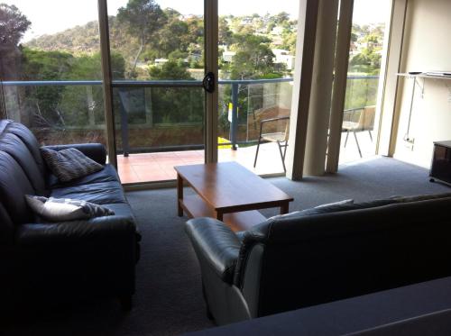 a living room with couches and a table and a large window at BlueWater Apartments in Merimbula