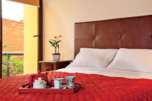 ein Bett mit einer roten Decke und ein Tablett mit Teebeuteln darauf in der Unterkunft La Morada Posada Boutique in Asunción