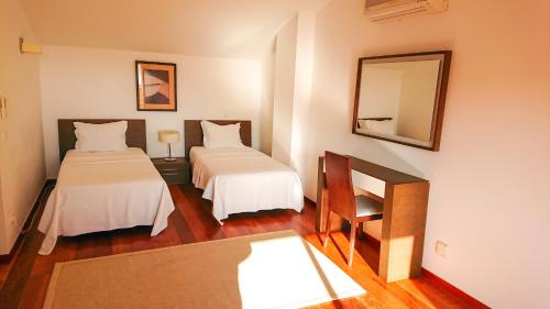 ルースにあるLuxury 3-bedroom apartment at high-end Praia da Luzのベッド2台と鏡が備わるホテルルームです。