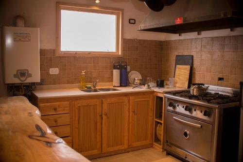uma cozinha com um fogão, um lavatório e uma janela em El Refugio Casa de Montaña em San Martín de los Andes