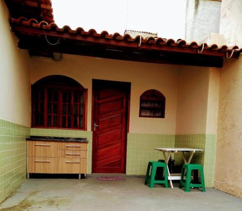 una casa con una puerta roja, una mesa y dos taburetes en Quitinete Cabo Frio , 300 metros da Praia do Forte, en Cabo Frío