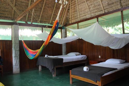 a room with two beds and a hammock in it at Paradise Amazon Tambopata Ecolodge in Puerto Maldonado