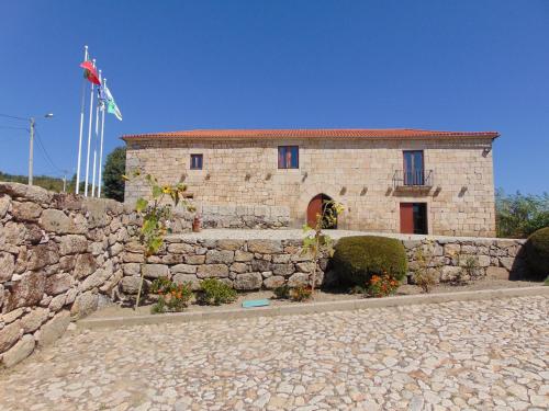 a stone building with a stone wall and a flag at Casa da Fonte in Tarouca