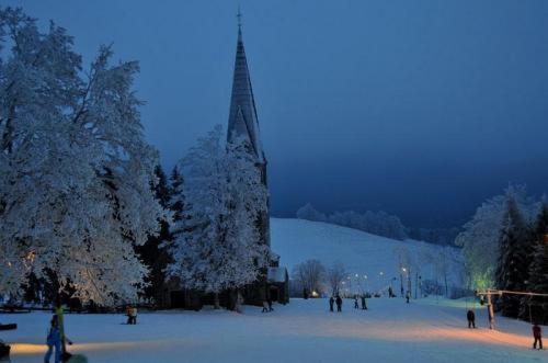 a group of people standing in the snow next to a tower at Hotel i Restauracja ABIS in Bystrzyca Kłodzka