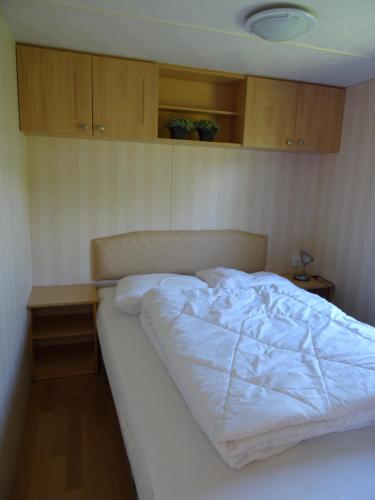 a bed in a bedroom with wooden cabinets at Chalet de Boshoorn in Serooskerke