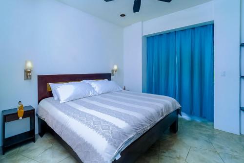 a bedroom with a large bed with a blue curtain at Makara Rio Suite / Ground Floor in Uvita