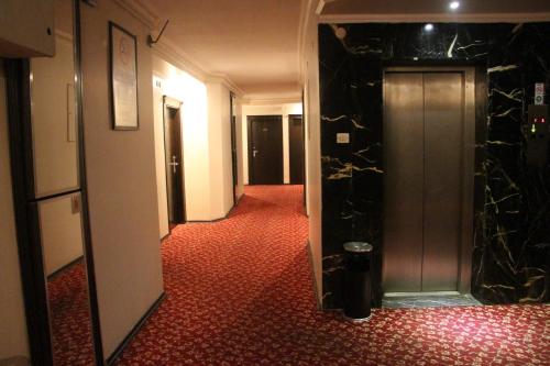 a hallway of a hotel with a door and red carpet at Akyuz Hotel in Ankara