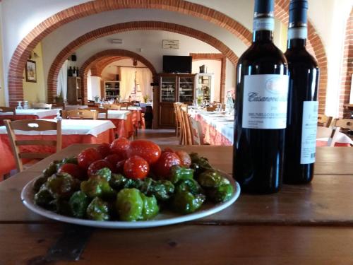 a plate of fruit on a table with two bottles of wine at Albergo La Foresteria in Bettolle