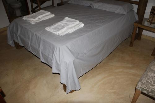 a bed with white sheets and white towels on it at Casa do Capão in Vale do Capao