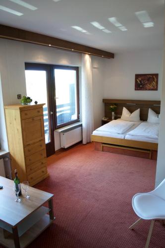 a hotel room with a bed and a table and two windows at Haus am Wald in Eltmann