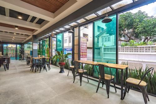 a restaurant with tables and chairs and large windows at Penyos Residence in Bangkok