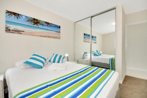 um quarto com uma cama com almofadas azuis e amarelas em Alex Beach Apt Bilgola4 em Alexandra Headland