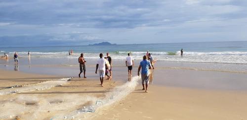 a group of people walking on the beach at Apto de 02 qtos no Ingleses - Florianopolis - SC in Florianópolis