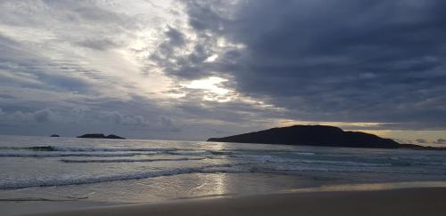 a beach with a cloudy sky and the ocean at Apto de 02 qtos no Ingleses - Florianopolis - SC in Florianópolis