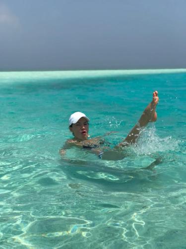 a woman swimming in the water in the ocean at Dive Villa Thoddoo in Thoddoo