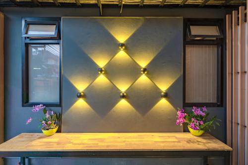a table with lights on a wall with flowers at Penyos Residence in Bangkok