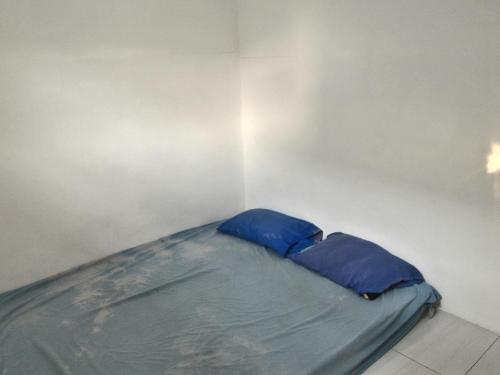 a small bed with blue pillows in a room at Kost 48 Surabaya in Surabaya