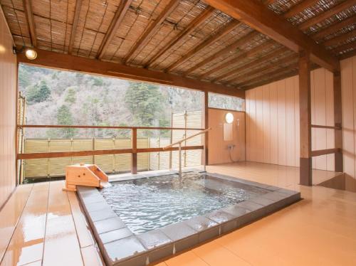 uma banheira de hidromassagem num quarto com uma grande janela em Kinugawa Royal Hotel em Nikko