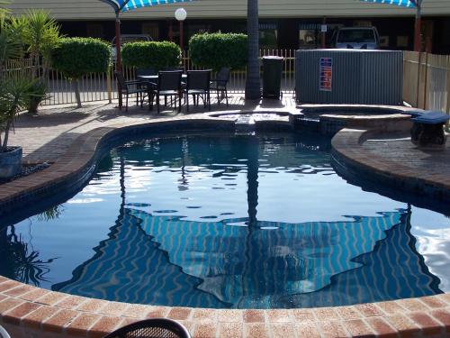 a swimming pool in a yard with a table and chairs at Macintyre Motor Inn in Goondiwindi
