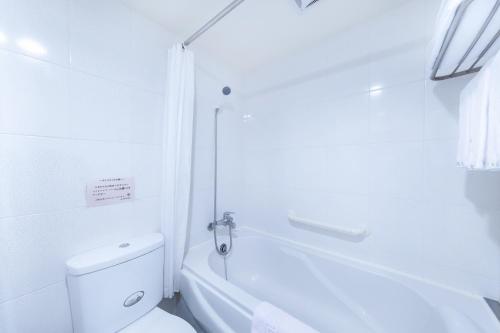 台北的住宿－洛碁大飯店山水閣，白色的浴室设有卫生间和浴缸。