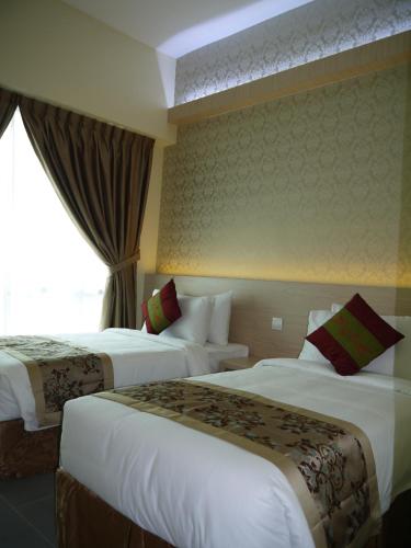 a hotel room with two beds and a window at MidCity Hotel Melaka in Malacca