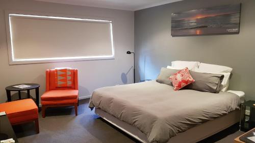 a bedroom with a bed with a window and a chair at The Edgewater on Greville in Sanctuary Point