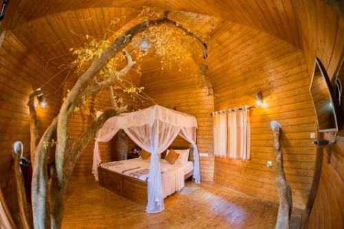 una camera da letto in una casa sull'albero con un letto di La Pentera a Hambegamuwa