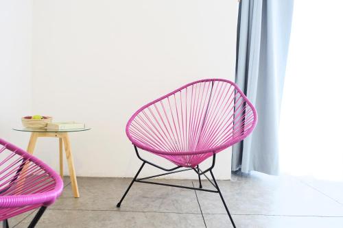 a pink chair and a table in a room at Hotel Mamá Carlota in Querétaro