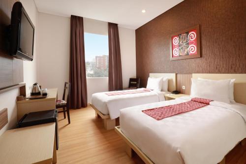 a hotel room with two beds and a television at Swiss-Belinn Panakkukang in Makassar