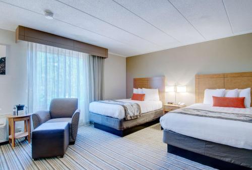 a hotel room with two beds and a chair at Best Western Plus Waltham Boston in Waltham