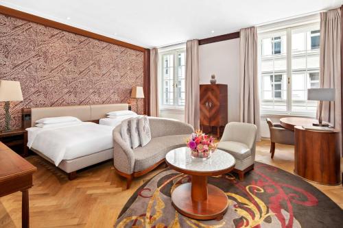 a bedroom with a bed and a couch and a table at Park Hyatt Vienna in Vienna