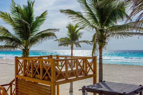 a wooden bench sitting on top of a sandy beach at Hyatt Zilara Cancun - All Inclusive - Adults Only in Cancún