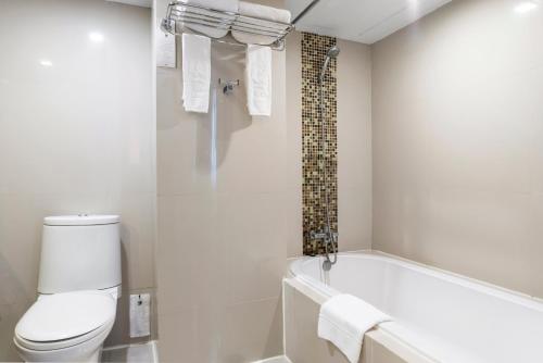 a white bathroom with a tub and a toilet at SC Park Hotel in Bangkok