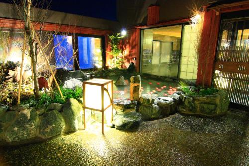 a garden with rocks and a sign in front of a building at Dormy Inn Hirosaki in Hirosaki