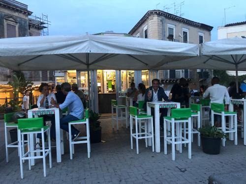 a group of people sitting at tables under an umbrella at Giupy Home in Catania