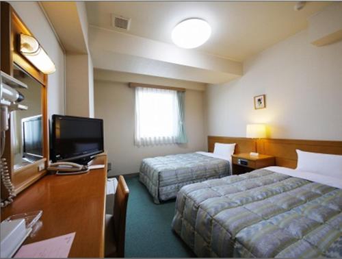 a hotel room with two beds and a flat screen tv at Hotel Route-Inn Nagoya Higashi Betsuin in Nagoya