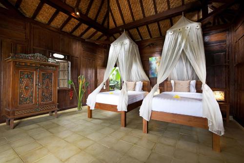 two beds in a room with wooden walls at Naya Ubud in Ubud