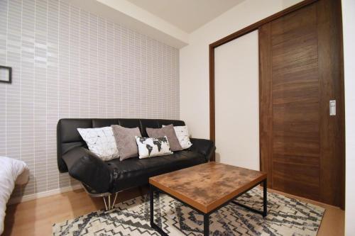 a black leather couch in a room with a table at Origami Residential Suite - Tokyo Asakusa Skytree in Tokyo