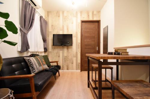 a living room with a black couch and a table at Origami Residential Suite - Tokyo Asakusa Skytree in Tokyo