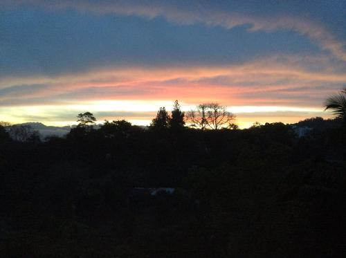 a sunset in the sky with trees in the foreground at Mount Haven in Kandy
