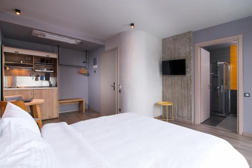 a bedroom with a large white bed and a kitchen at Urban Donkey in Thessaloniki
