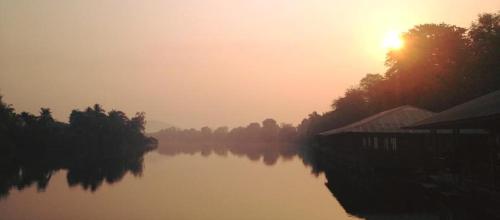 a view of a river with the sun setting in the background at Duenshine Resort in Kanchanaburi